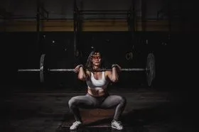 Coach guiding a member through a barbell squat